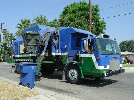 Workers handling commercial waste containers during collection